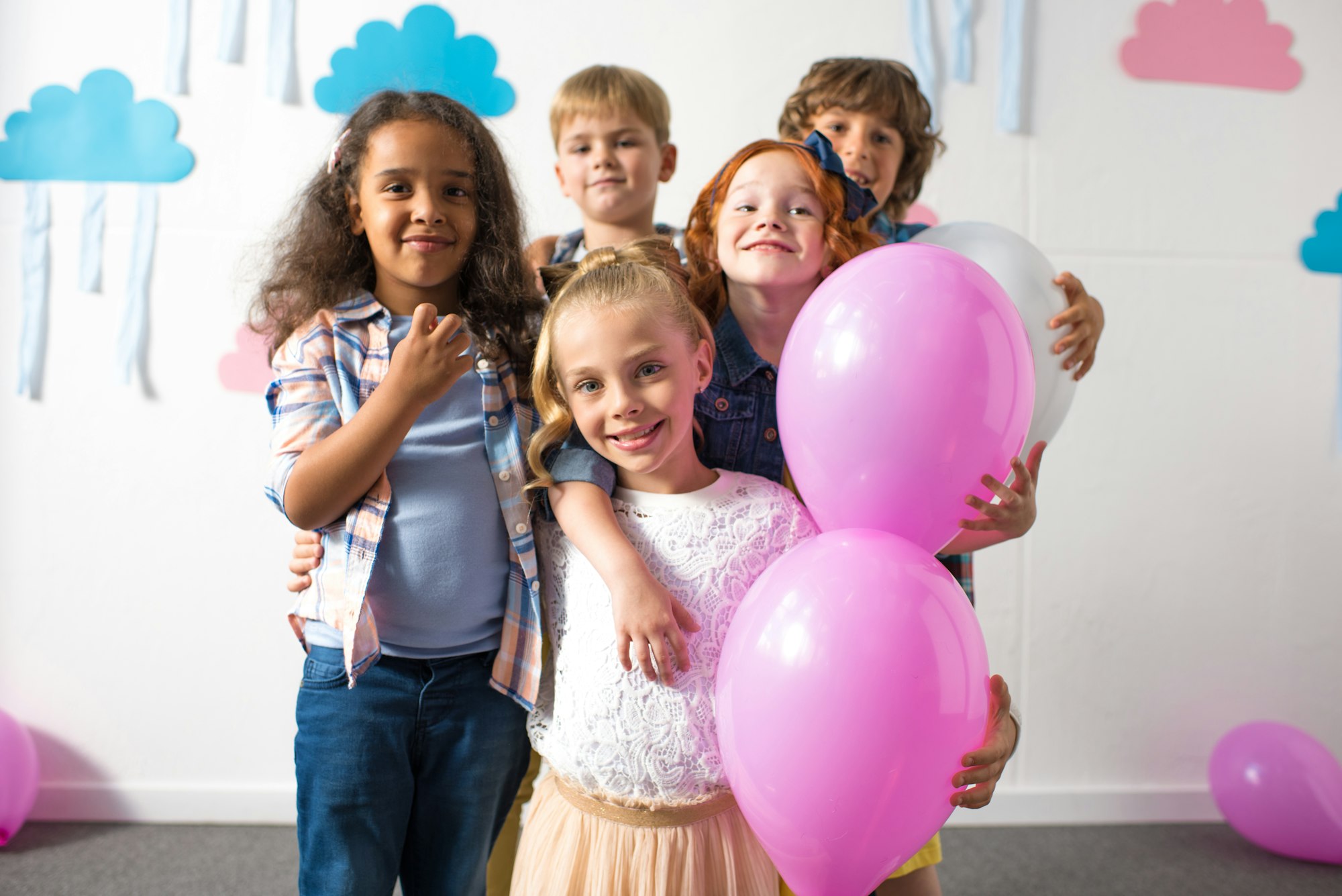 adorable multiethnic kids holding balloons and smiling at camera at birthday party